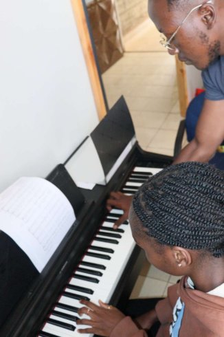 Music student taking piano lessons at home in Nairobi